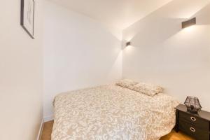 a white bedroom with a bed and a night stand at L'Appartement d'Art et de Lumière in Clichy