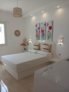a white bedroom with a large bed with flowers on the wall at Klimataria Studios in Agios Prokopios