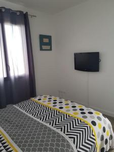 - une chambre avec un lit et une télévision murale dans l'établissement Mini villa 84 sur la route des vins, à Sainte-Cécile-les-Vignes