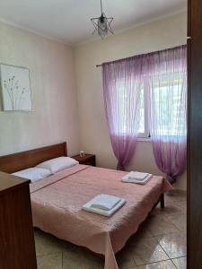 a bedroom with a bed and a window with purple curtains at Xristos Villa in Nea Vrasna