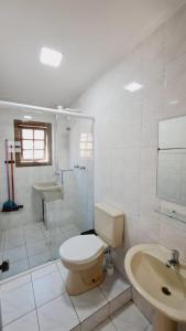 uma casa de banho com um WC, um chuveiro e um lavatório. em Recanto Do Sol Bertioga em Bertioga