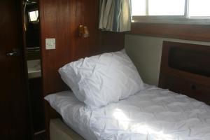 a white bed in a room with a window at The Rose - 37ft Lakeside Yacht with Hot Tub in Swansea