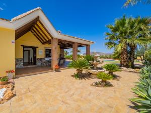 a patio with palm trees and a yellow house at Cubo's Casa El Jazmin High Privacy in Alhaurín el Grande