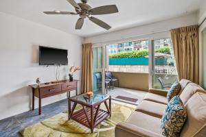 a living room with a couch and a tv at 2Br Kauai Kailani Condo, Pool, walk to Ocean & Shops, AC KK117 in Kapaa