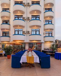 a long table with blue chairs in front of a building at Hotel Sapphire in Mombasa