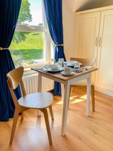 mesa y sillas en una habitación con ventana en Mount Edwards Hill Guest Accommodation en Cushendall