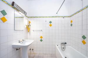 a white tiled bathroom with a sink and a tub at Quinta das Varandas by Umbral in Vila Nova de Milfontes