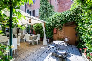 un patio esterno con tavoli, sedie e edera di Hotel Apostoli Garden a Venezia