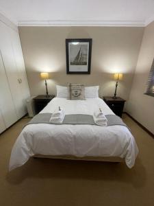 a bedroom with a large white bed with two towels on it at DullVino Apartment @ Millers Cove in Dullstroom