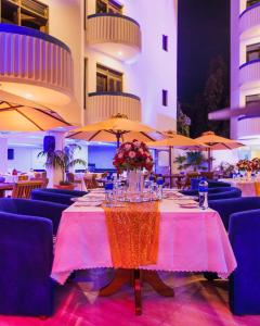 Hotel Sapphire في مومباسا: طاولة في المطعم مع الكراسي والمظلات