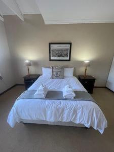 a bedroom with a large white bed with two pillows at DullVino Apartment @ Millers Cove in Dullstroom