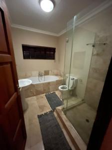 a bathroom with a shower and a tub and a toilet at DullVino Apartment 8 at Millers Cove in Dullstroom +15 photos