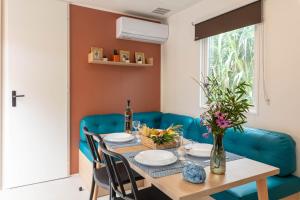 a dining room with a table and blue chairs at Le Palmier, mobil-home sans vis-à-vis idéalement situé entre mer et vignes in Hyères