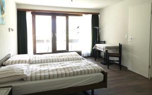 Schlafzimmer mit einem Bett, einem Fenster und einem Schreibtisch in der Unterkunft Aparthotel Résidence Bernerhof in Wengen