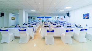 une salle de banquet avec des tables blanches et des chaises bleues dans l'établissement Hotel Sapphire, à Mombasa