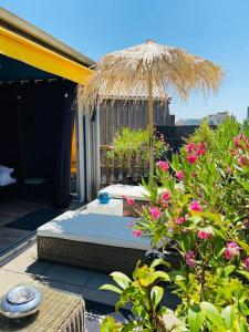uma cama com um guarda-chuva de palha e algumas flores cor-de-rosa em Loft atypique13Om2 rooftop et patio,dep tardif PKG,AC em Bordeaux