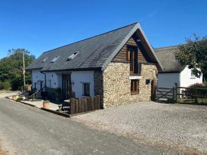 a stone house with a black roof on a road at Hay Loft in Bideford
