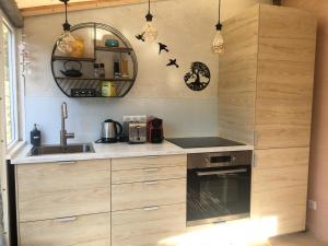 eine Küche mit Holzschränken, einem Waschbecken und einem Spiegel in der Unterkunft Les Ilets de L'Eau Blanche in Cavalaire-sur-Mer