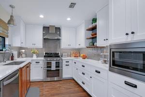 a kitchen with white cabinets and stainless steel appliances at Coachman Cottage in Wimberley