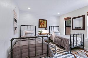 two beds in a bedroom with white walls and a mirror at Coachman Cottage in Wimberley