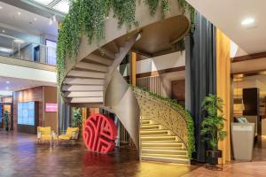 a spiral staircase in a lobby with plants at NH Collection Berlin Mitte am Checkpoint Charlie in Berlin