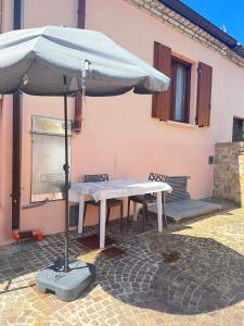een tafel met een paraplu voor een gebouw bij Casa AmeRosa in Fiorenzuola di Focara