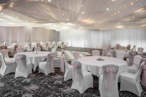 un salón de banquetes con mesas y sillas blancas y techo en Norton Park Hotel, Spa & Manor House - Winchester en Sutton Scotney