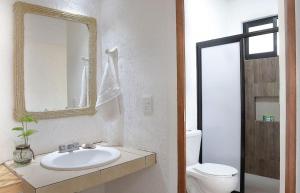 a bathroom with a sink and a toilet and a mirror at Casa Yoo Bigu Mazunte in Mazunte