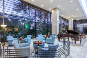 a lobby with a piano and tables and chairs at NH Cali Royal in Cali