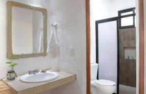 a bathroom with a sink and a toilet and a mirror at Casa Yoo Bigu Mazunte in Mazunte