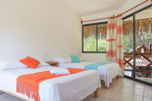 two beds in a room with a window at Casa Yoo Bigu Mazunte in Mazunte