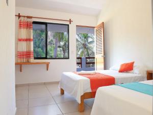 a bedroom with two beds and a window at Casa Yoo Bigu Mazunte in Mazunte