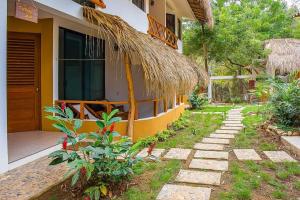 a house with a thatch roof and a walkway at Casa Yoo Bigu Mazunte in Mazunte