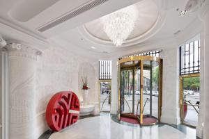 a lobby with a chandelier and a red chair at NH Collection Madrid Paseo del Prado in Madrid