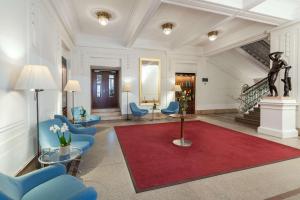 een lobby met blauwe stoelen en een rood tapijt bij NH Wien Belvedere in Wenen