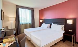 um quarto com uma grande cama branca e uma parede vermelha em NH Coimbra Dona Ines em Coimbra