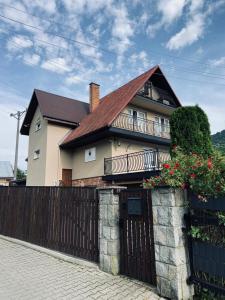 a house with a fence and a gate with flowers at Na Świerkowym Strychu in Szczawnica