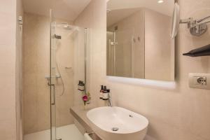 uma casa de banho branca com um lavatório e um chuveiro em NH Milano Corso Buenos Aires em Milão