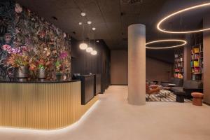 a lobby with a bar with flowers on the wall at NH Milano Corso Buenos Aires in Milan