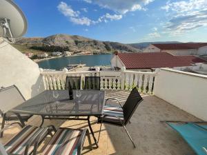 a table and chairs on a balcony with a view of the water at Apartments Niko Metajna, island Pag in Metajna