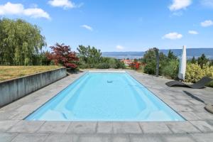 a swimming pool in the backyard of a house at Magnifique villa avec piscine et vue sur le lac in Cudrefin