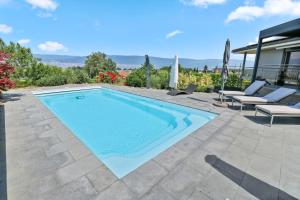 a swimming pool with two lounge chairs and a house at Magnifique villa avec piscine et vue sur le lac in Cudrefin