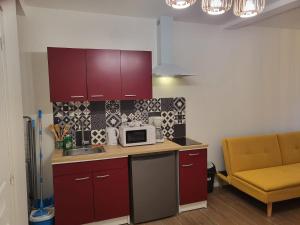 a kitchen with red cabinets and a microwave on a counter at Studio ruffec 10 in Ruffec