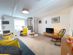 a living room with a couch and a tv at Sixpence Cottage, a few steps from the harbour! in St Ives