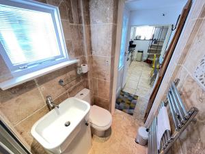 a bathroom with a sink and a toilet and a window at Sixpence Cottage, a few steps from the harbour! in St Ives +24 photos