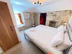 a bedroom with a bed and a stone wall at Sixpence Cottage, a few steps from the harbour! in St Ives