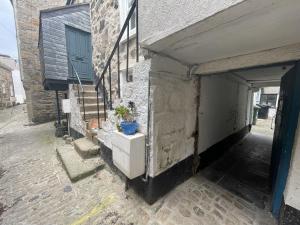 a building with a door and a plant on a dresser at Sixpence Cottage, a few steps from the harbour! in St Ives