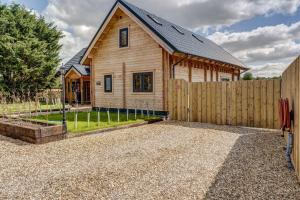 una casa de madera con una valla y un patio en Bluebell Lodge, en Benson