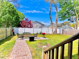 a backyard with benches and a table and a fence at Peaceful home equal to a sound sleep! in Mastic Beach