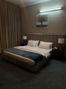 a bedroom with a large bed with two lamps and a painting at Crystal Blue Hotel in Rabigh